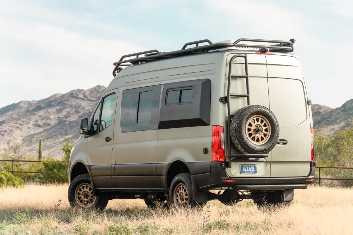 shop camper vans for sale Tommy camper van with a roof rack and rear ladder, parked in the desert