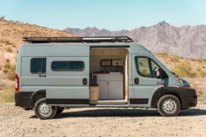 Side view of the Ram Promaster camper van with roof rack below desert mountains
