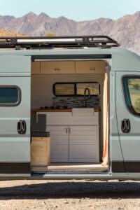 Close-up through the sliding door of the galley with white cabinets and teak countertop