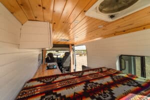 Bed and overhead cabinets under the knotty pine ceiling
