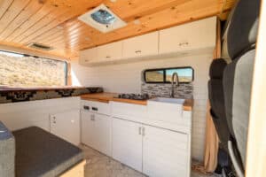 Galley with white cabinets, teak countertop, farm sink and overhead cabinets