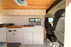 White galley cabinets and overhead storage beside the cab seats