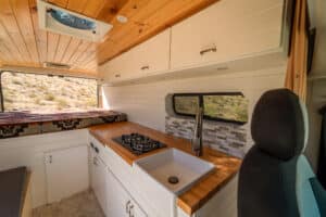 Galley with farm sink, gooseneck faucet and stovetop next to the swivel seat