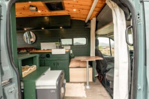 Interior with galley, overhead cabinets and Dometic fridge under the wood ceiling