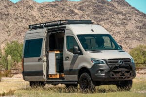 Sprinter Maddox camper van parked below desert mountains, sliding door open