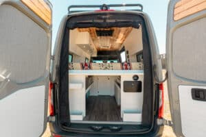 Rear doors open on the Sprinter showing the bed platform storage