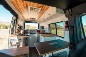 Galley and dinette of the Sprinter Maddox van with white cabinets and teak butcher block countertops