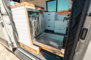 Shower area with pan and white wall panels inside the Sprinter camper van