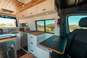 Galley with white cabinets, teak countertop and Lagun table beside the swivel seat