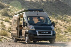 Front view of the Ram ProMaster camper van showing the RAM grille, roof rack and open side door